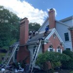 Crew working on a roof with ladders