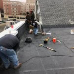 Crew working on a flat roof in downtown Malden