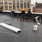 Crew installaing flat roof in downtown Malden